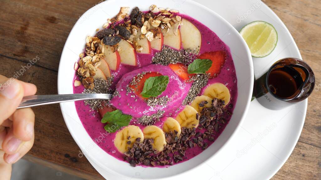 Top view of a spoon in dragon fruit smoothie bowl. Healthy vegan breakfast concept