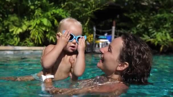 Glückliche Kindheit. Junge kaukasische Mutter spielt mit ihrem fröhlichen Baby im Schwimmbad — Stockvideo