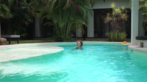 Conceito de férias de luxo. Mulher branca nadando em sua piscina privada em sua villa. — Vídeo de Stock