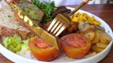 Çatal bıçak takımı domatesi keser ve kameraya gösterir. Bitki bazlı kızartma tarifi