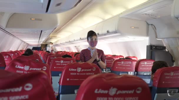 Aziatische stewardess draagt gezichtsmasker waarop de nooduitgang in een vliegtuig te zien is.Gezondheidszorg in transportconcept.Bali-juni-2021 — Stockvideo