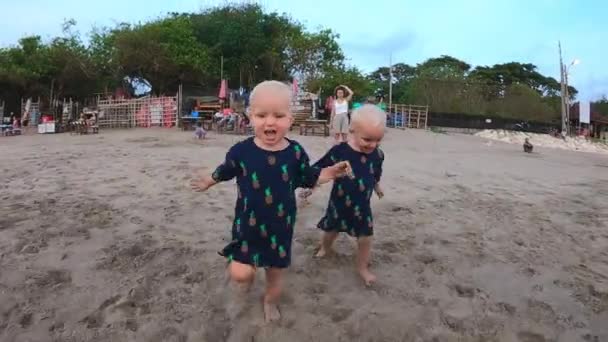 Dos gemelas rubias adorables corriendo en la playa hacia la cámara — Vídeo de stock