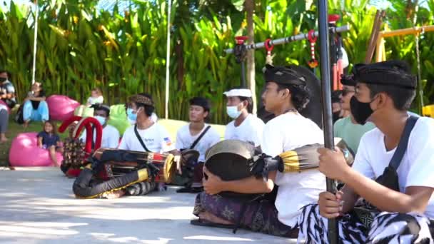 Balinesiska musiker som sitter på marken under rituella danser bär ansiktsmasker. Bali-maj-2021 — Stockvideo