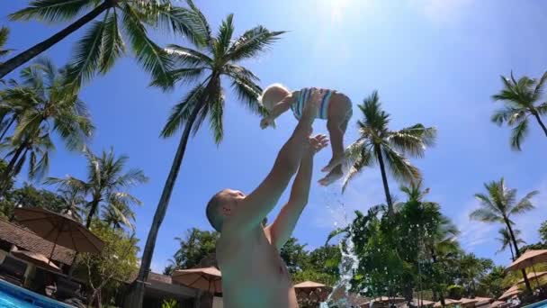 Perfekter tropischer Familienurlaub. Junger kaukasischer Vater wirft seine kleine Tochter in die Luft. — Stockvideo