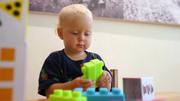 Como manter uma criança ocupada. Construção de edifício de bebê caucasiano com tijolos de brinquedo — Vídeo de Stock