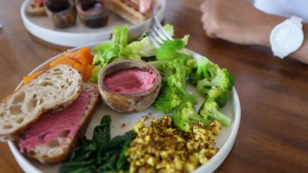 Fork dipping broccoli in a beetroot sauce. Healthy balanced nutritious vegan meals full of vegetables and plant based proteins — Stock Video