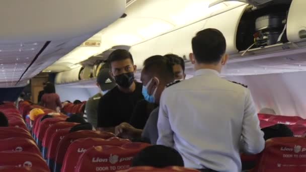 搭乗員は、乗客が航空機内で座っているのを見つけるのを助けます。 — ストック動画
