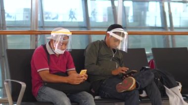 Maskeli adamlar istasyonun bekleme odasında oturuyorlar. Bali-Haziran-2021