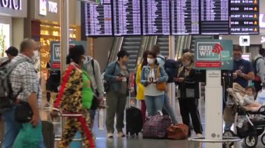 Covid-19 salgını sırasında kamusal alanlar. Tren istasyonundaki yolcular kalkış tahtasının altında Bali-Haziran-2021 yolculukları hakkında bilgi almak için bekliyorlar.