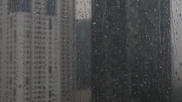 Lluvia cae en una ventana. Vista de rascacielos — Vídeo de stock