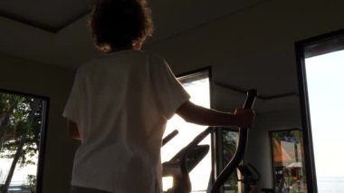 Modern şık bir spor salonunda, eliptik bir antrenörle çalışan bir kızın arka planı. 