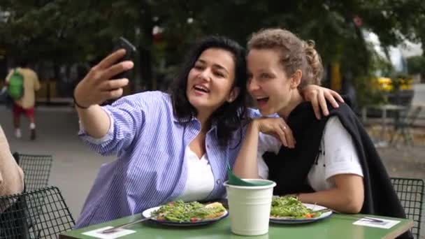 Sağlıklı öğle yemeğinde genç ve neşeli kadınlar selfie çekiyorlar. Hafta sonları arkadaşlarla şehirde güzel vakit geçirmek. — Stok video