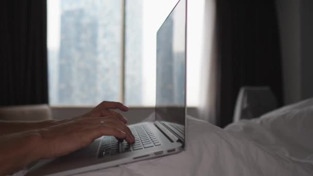 Sluiten van de handen van een persoon in bed typen op laptop. Begrip thuiskantoor — Stockvideo