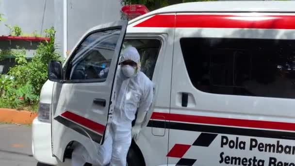 Läkare täckt av personlig skyddsdräkt som lämnar ambulansen.Säkerhetsutrustning för att förhindra koronavirus. Bali-juni-2021 — Stockvideo