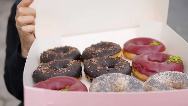 Primer plano de la persona que abre una caja con una docena de rosquillas veganas coloridas — Foto de Stock