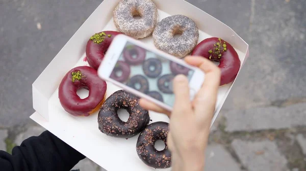 Vista superior de tomar fotos de una docena de donas veganas orgánicas en un teléfono inteligente. Concepto blog de alimentos — Foto de Stock