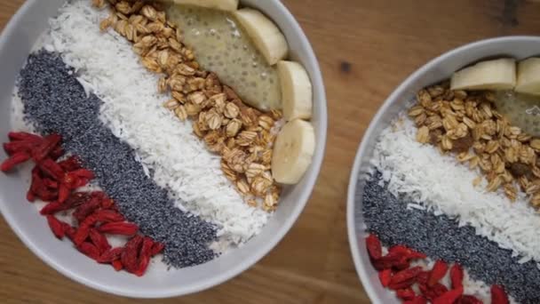 Frühstück an Feiertagen. Draufsicht auf zwei Smoothie-Schalen mit Banane, Samen und Goji-Beeren — Stockvideo