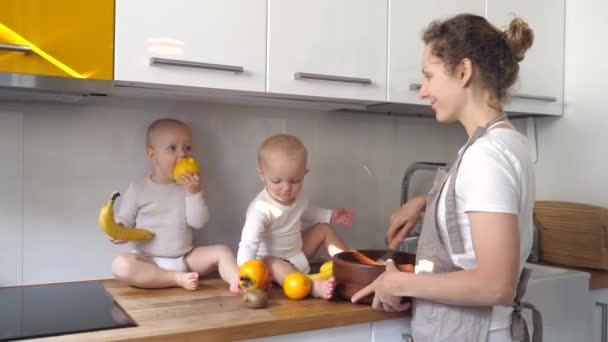 Справжнє життя матері. Діти грають з фруктами, сидячи на столі, змішуючи соус — стокове відео