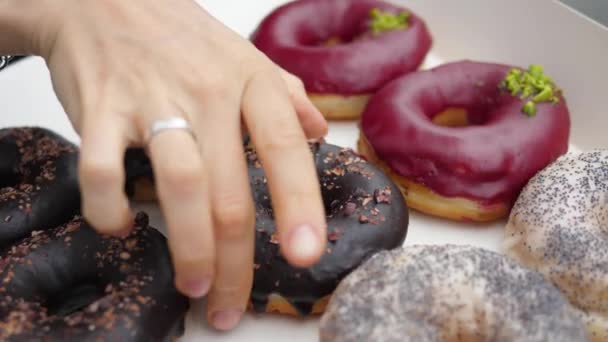 Primo piano di una mano che raccoglie una ciambella sana a base di piante organiche da una scatola. — Video Stock