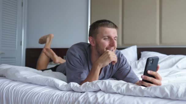 En kaukasisk man som ligger på en säng och pratar med nära och kära. Begreppet social isolering — Stockvideo