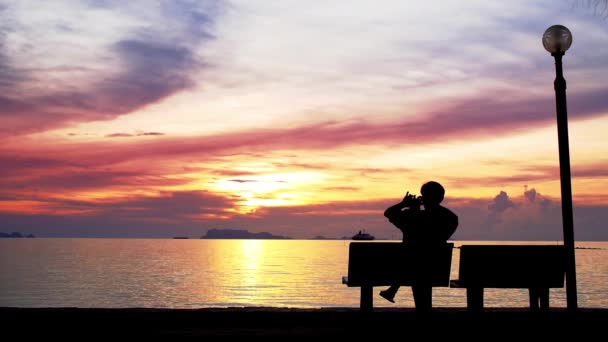 Mens geniet van de zonsondergang en neemt een foto. — Stockvideo