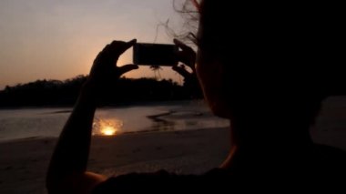 Sahilde günbatımı telefon ile resim çekmek kadın silüeti