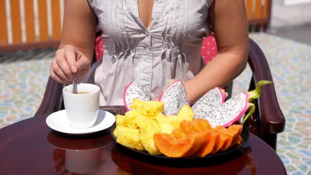 Nő, friss gyümölcsöt, és egy csésze teát reggelizik — Stock videók
