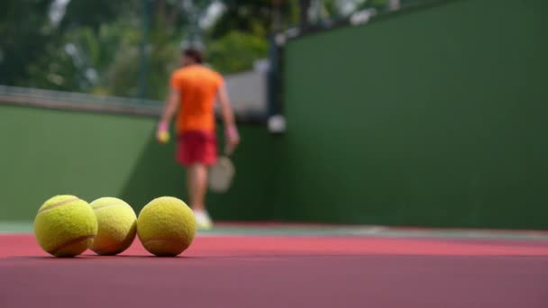 Tennisspeler afspelen op baan met tennisballen. — Stockvideo