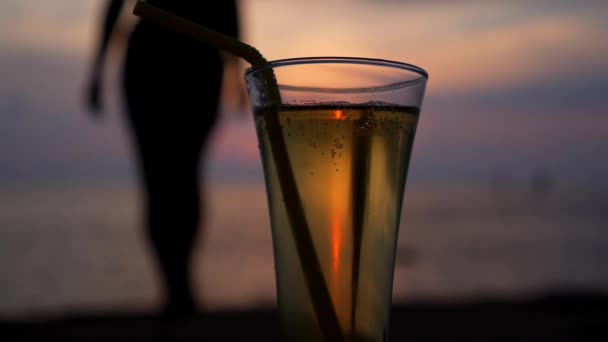 Silueta femenina y vaso de bebida refrescante al atardecer — Vídeo de stock