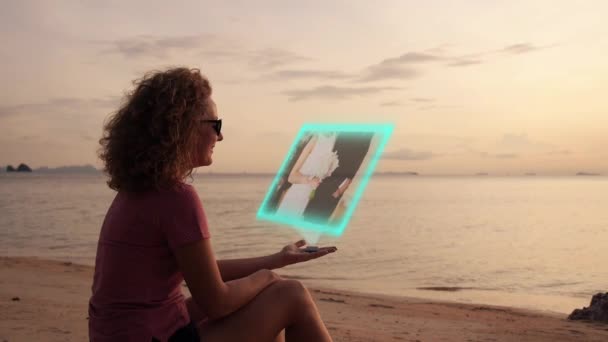 Kvinna titta på Video på virtuella Hologramic median anordning på stranden. Futuristiska högteknologiska koncept. — Stockvideo