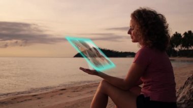 Kız fütüristik Hologramic medya aygıtı ile sahilde. Yüksek teknoloji kavramı.