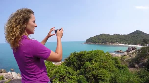 Denizde telefon fotoğraf makinesi kullanan mutlu genç kadın. Ağır çekim. — Stok video