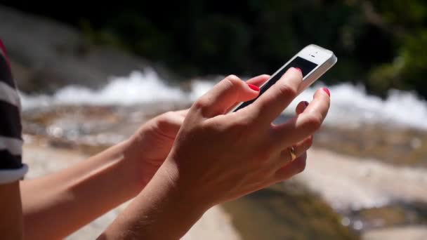 Primer plano de la mano femenina usando un teléfono inteligente al aire libre . — Vídeo de stock