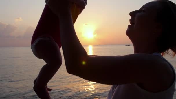Mutter und Baby bei Sonnenuntergang am Meer. Zeitlupe. — Stockvideo