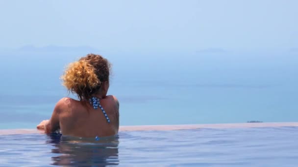 Молодая женщина отдыхает в бассейне летом — стоковое видео