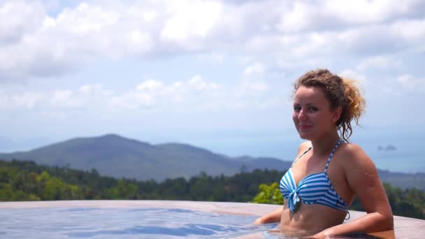 Schöne Frau entspannen im Infinity-Pool im Urlaub — Stockvideo