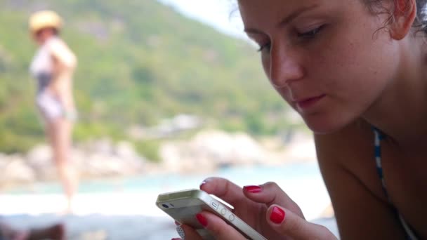 Pretty Teenager Girl Using a Smart Phone on Beach in summer — стоковое видео