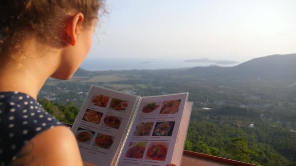 Jovem Mulher Olhando para Menu em Restaurante com Vista Bonita — Vídeo de Stock