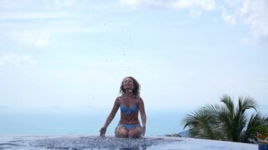 Genç kadın bikini sonsuz yüzme havuzunda. Ağır çekim.
