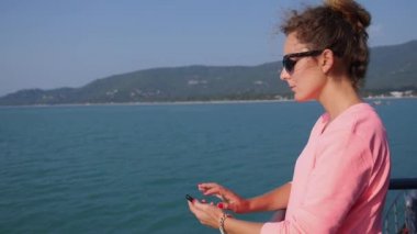 Denizde teknede yelken Smartphone kullanan genç kadın