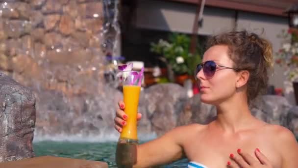 Ung kvinna dricka fruktjuice i poolen — Stockvideo