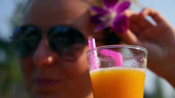 Mujer joven con cóctel de frutas Relajante bajo la luz del sol — Vídeo de stock