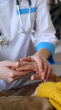 Bir sağlık uzmanının, yaşlı bir kadının elini nazikçe tutarak, bir hastanede ya da bakımevinde rahatlık, destek ve tıbbi bakım sağlaması.