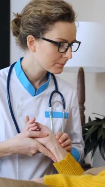 Evde yaşlı bir hastayı ziyaret eden, elini tutan ve nabzını dikkatlice kontrol eden, ev sağlığı ziyareti sırasında destek ve tıbbi bakım sağlayan bir kadın doktor.