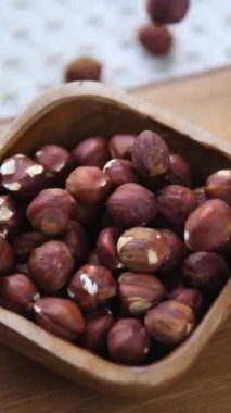 Organik kabuklu fındıkların yavaşça güzel bir ahşap kaseye düşmesi, sağlıklı beslenmenin, besleyici atıştırmanın ve doğal besin maddelerinin mükemmel bir temsili.