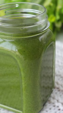 Taze yapılmış yeşil detoks smoothie yavaş yavaş cam mason kavanozunda dönüyor, dengeli bir diyet için vitamin ve besin dolu sağlıklı bir vegan içecek, canlı, organik bir yaşam tarzı sergiliyor.
