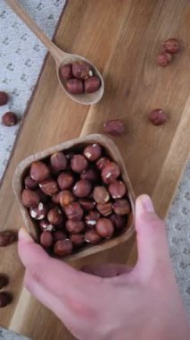 Tahta bir kasede taze fındıklar elle kesme tahtasının üzerine yerleştirilir, sağlıklı beslenmek ve vejetaryen yaşam tarzı kavramları için mükemmel bir kırsal ve doğal gıda sahnesi oluşturulur.