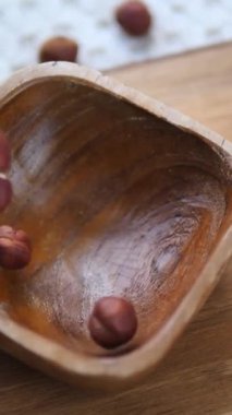 Organik fındıklar yavaş çekimde kırsal bir ahşap kaseye düşüyor, vitamin ve proteinle dolu sağlıklı bir aperatif, refah kavramını, doğal bileşenleri ve sağlıklı beslenmeyi temsil ediyor.