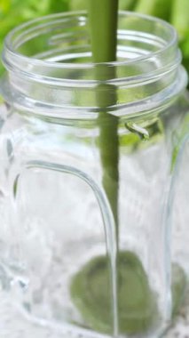 Sağlıklı yeşil sebze suyu temiz bir cam mason kavanozuna dökülüyor, canlı bir yaşam tarzı, detoks ve taze organik malzemelerle temiz yemek için besleyici bir içeceği vurguluyor.