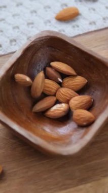 Lezzetli çiğ bademlerin yavaş çekimde güzel bir ahşap kaseye düşmesi sağlıklı bir diyet, organik gıda ve vejetaryen bir atıştırmalık için besleyici bir bitki proteini vurguluyor.